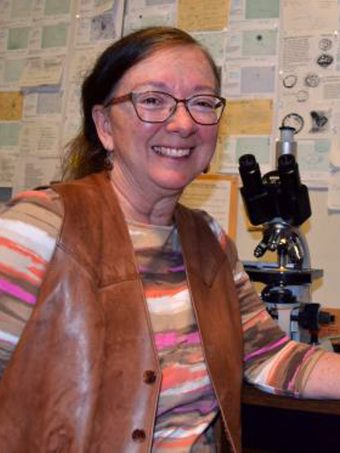An image of Deborah Pearsall, smiling and posing in her lab.